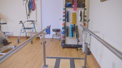 A physical therapy room featuring parallel bars and various exercise tools for rehabilitation.