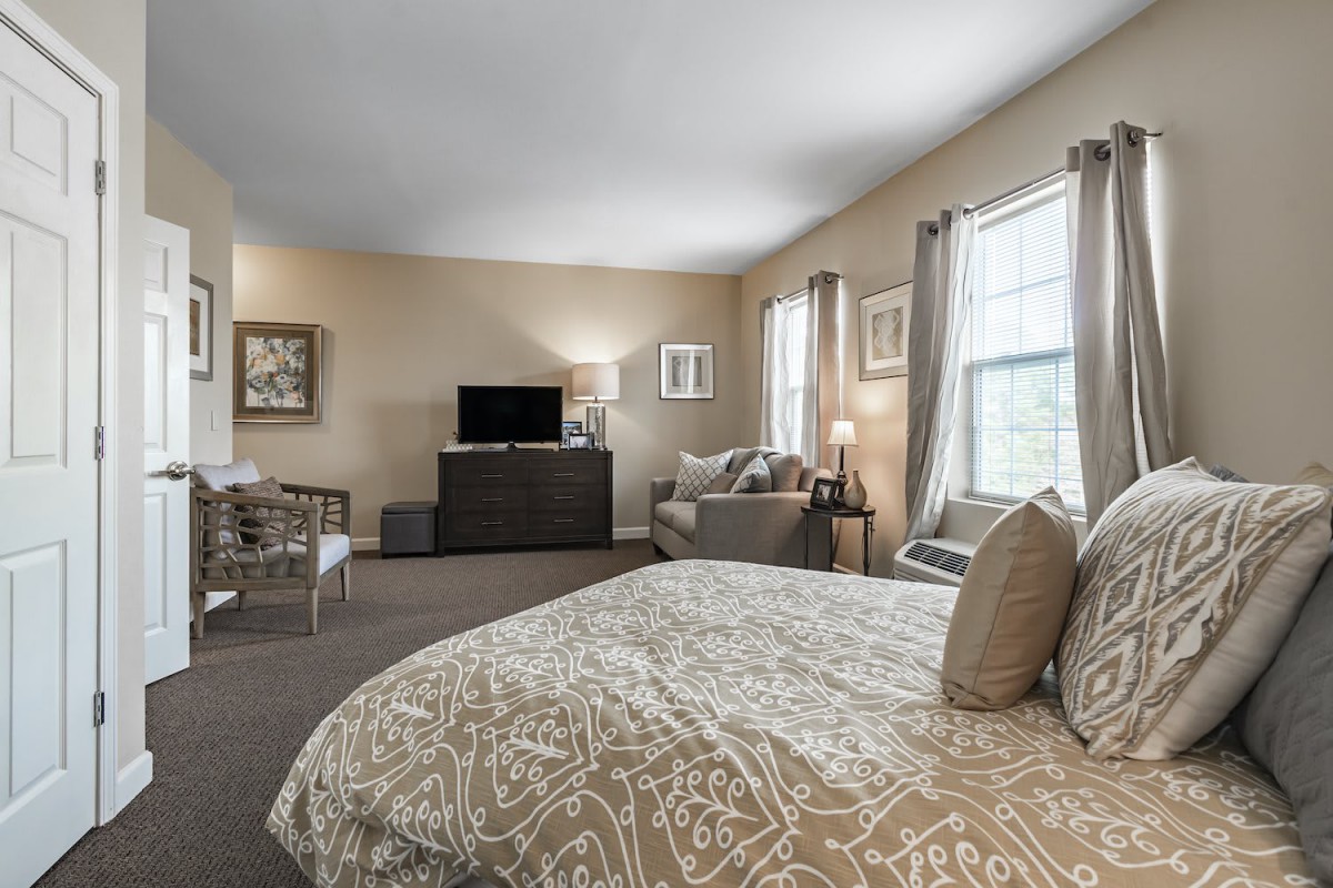 Spacious bedroom with a cozy seating area and modern decor.
