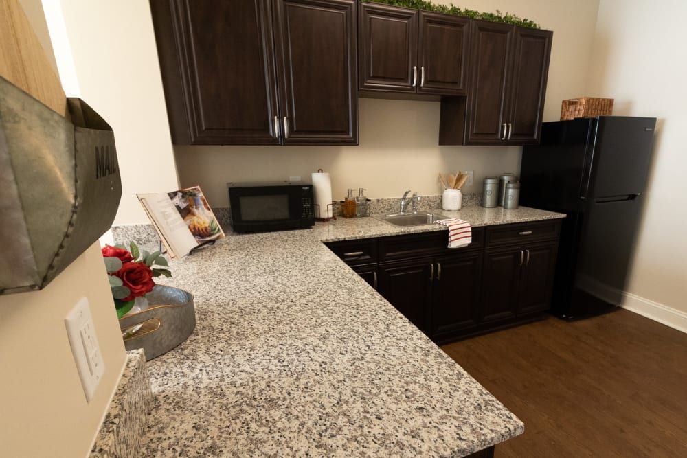 Modern kitchen with granite countertops and dark wooden cabinets.