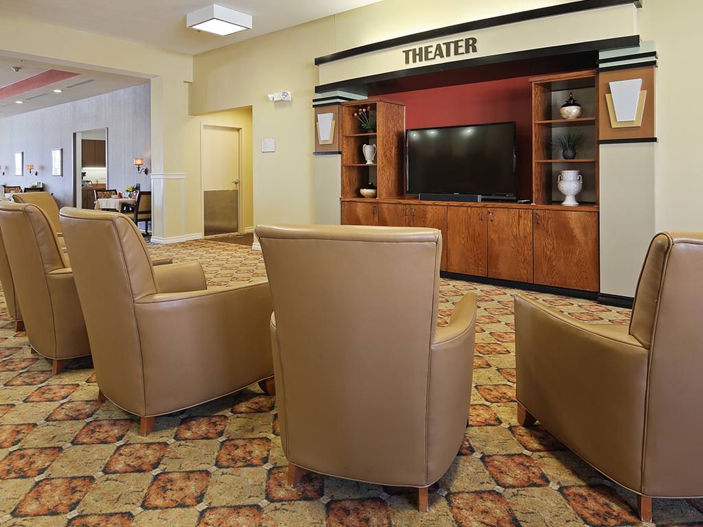 A cozy theater room with armchairs facing a large television, designed for relaxation and entertainment.