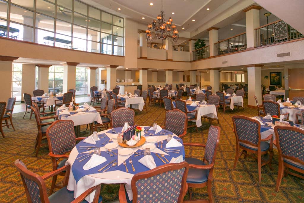 An elegantly set dining area with multiple tables, chairs, and a chandelier.