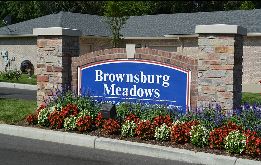 Entrance sign for Brownsburg Meadows surrounded by colorful flowers and brickwork.