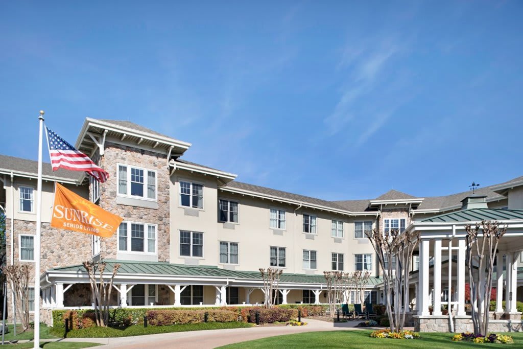 A large residential building with a well-maintained lawn and clear blue sky overhead.