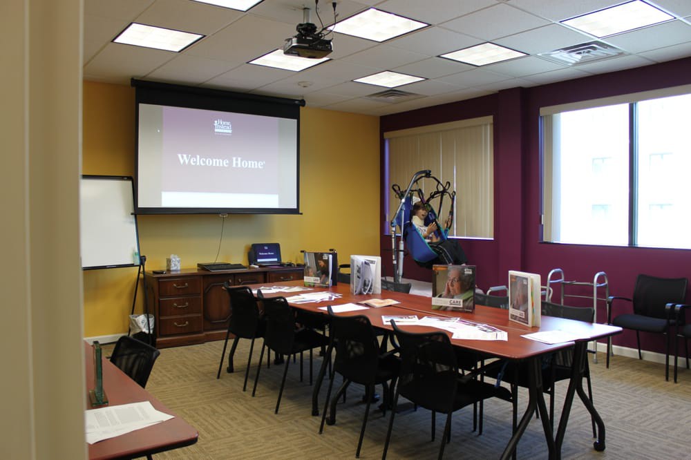 An empty conference room set up for a meeting or presentation, featuring a projector screen and neatly arranged tables and chairs.