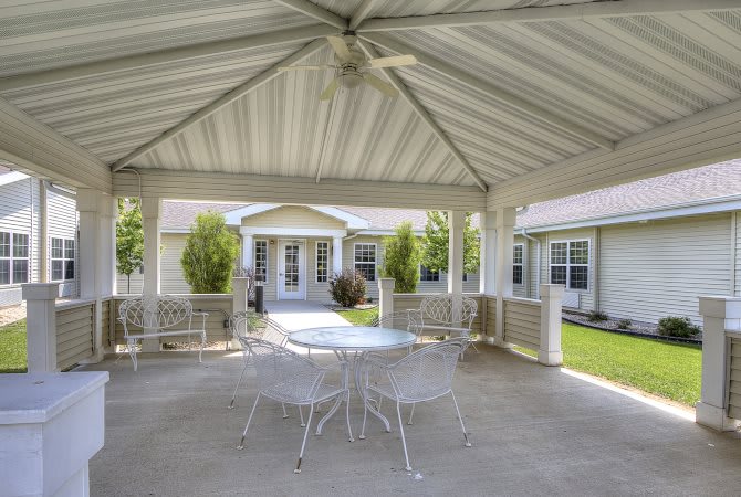 A cozy gazebo in the backyard with a table and chairs, perfect for outdoor relaxation.
