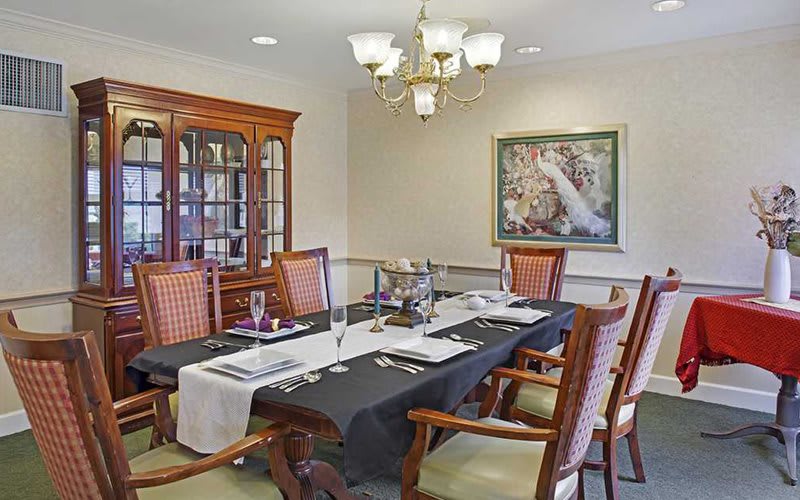 A well-decorated dining room with a large table, elegant chairs, and a chandelier.