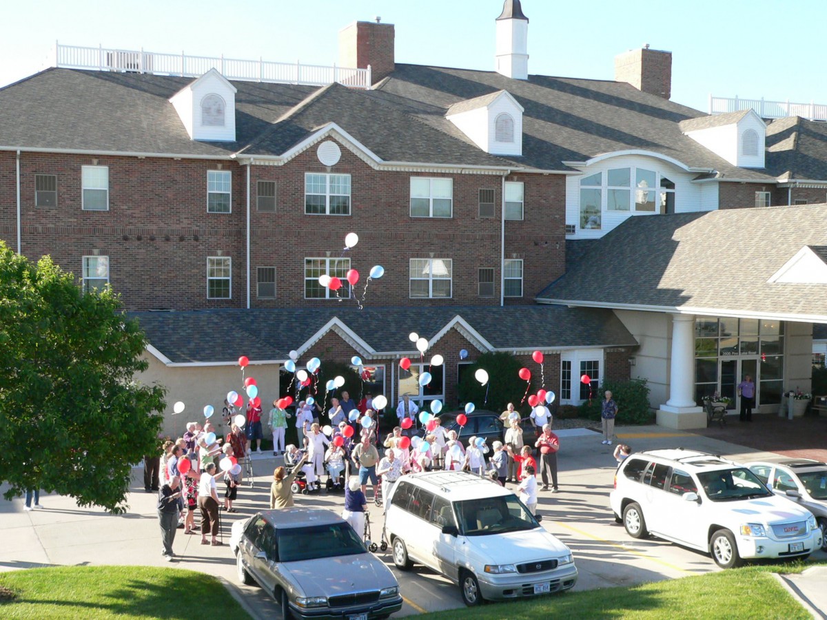 A large group of people celebrating with balloons outside a building.