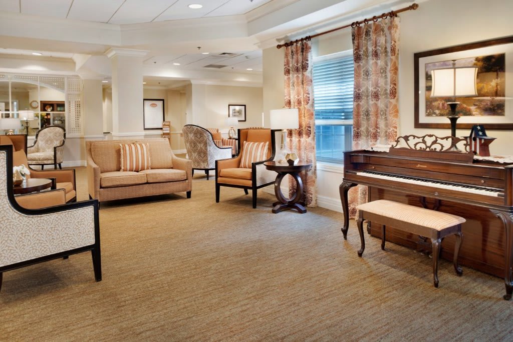 A cozy living room with elegant furniture and a piano by the window.