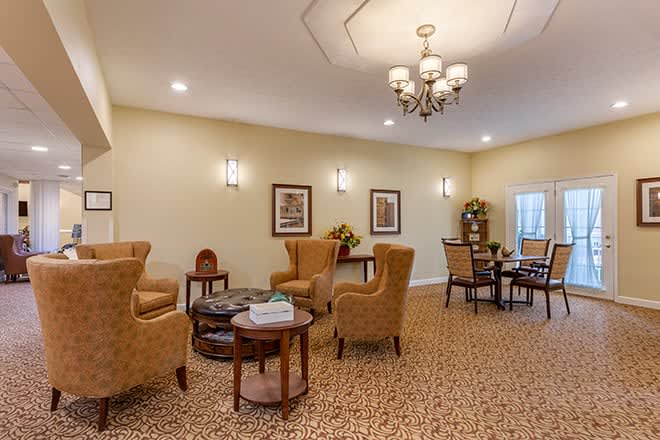A cozy living room interior featuring comfortable seating, a chandelier, and a carpeted floor.