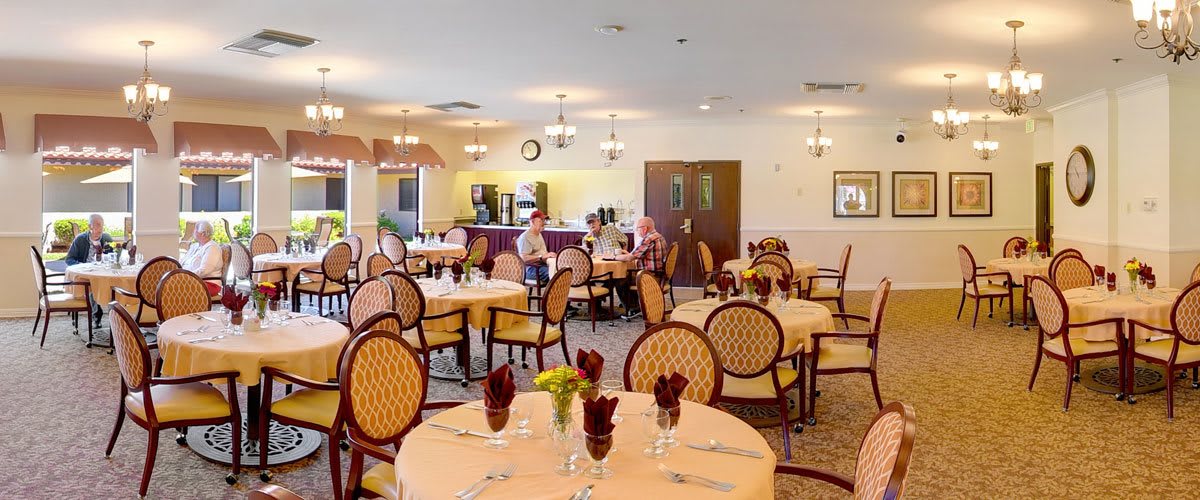 A spacious dining room with elegantly set tables and chairs, ready for guests.
