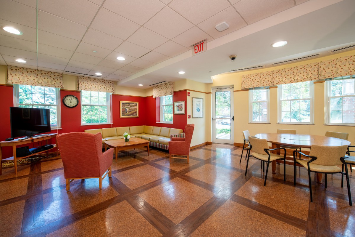 A cozy lounge area with seating, tables, and bright windows.