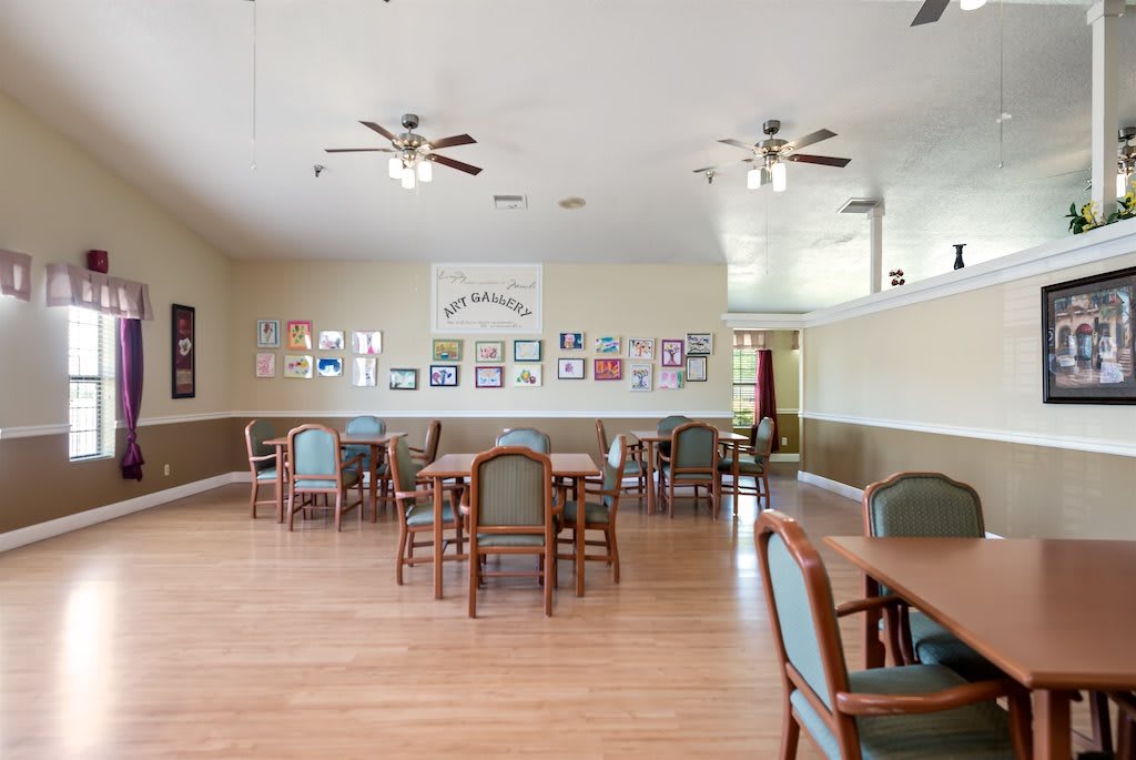 A classroom setting with tables and chairs, decorated walls, and ceiling fans.