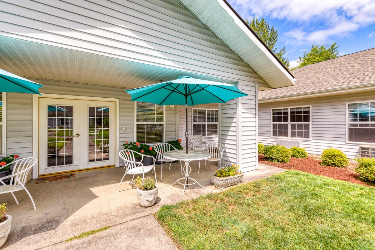 A cozy patio with a table, chairs, and an umbrella, set in the backyard of a house.