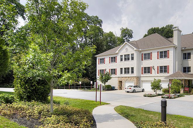 A suburban house with a driveway, surrounded by trees and an overcast sky.