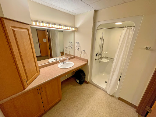 A well-lit bathroom featuring a sink, mirror, and a shower area.