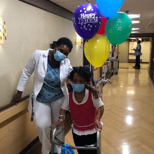A joyful moment in the hospital as a child celebrates with balloons, guided by a caring nurse.