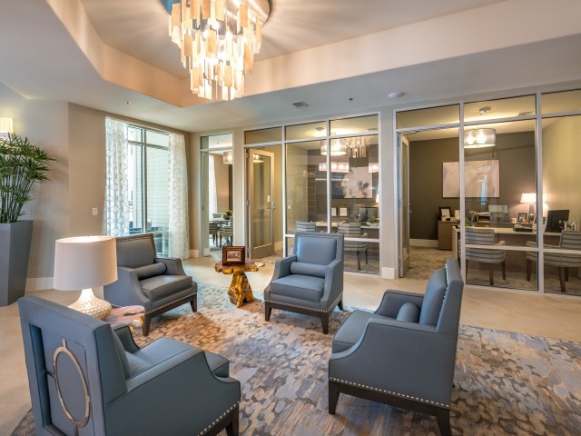 A stylish and modern seating area with plush armchairs and a chandelier, set in a contemporary office or living room space.