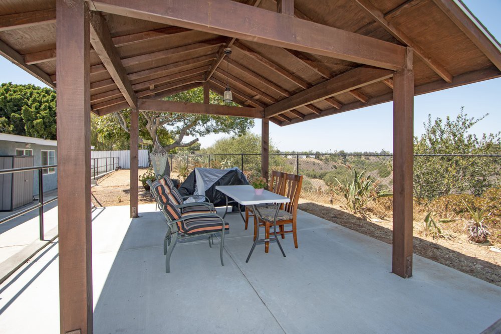 A cozy outdoor patio with a pergola, featuring a table and seating set against a scenic backdrop.