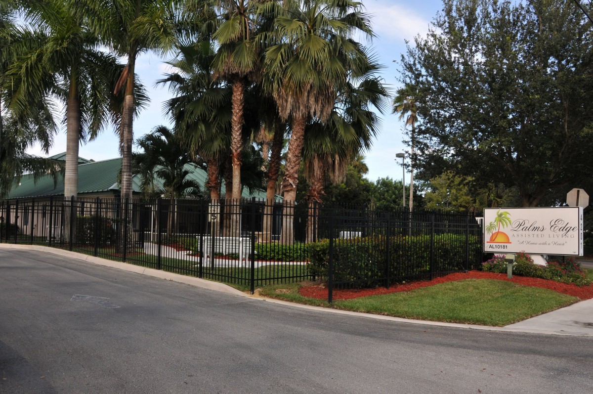 Entrance to a gated community with palm trees and well-maintained landscaping.