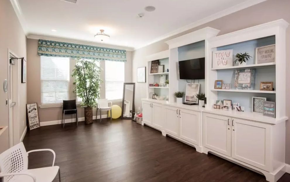 A modern living room with built-in shelving, a large flat-screen TV, and abundant natural light.