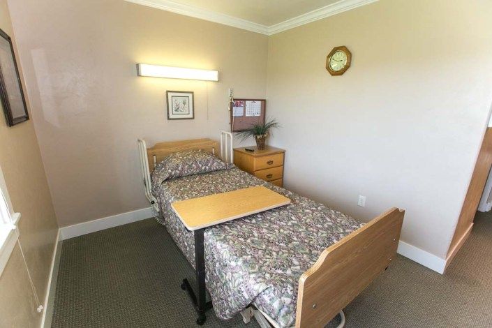 A simple room with a hospital bed and a bedside table.