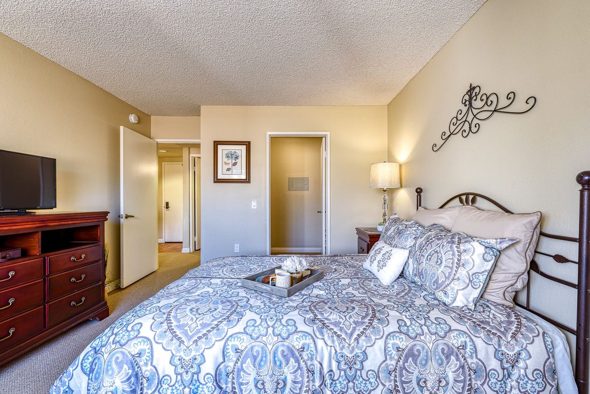 A cozy bedroom with elegant bedding and warm lighting.