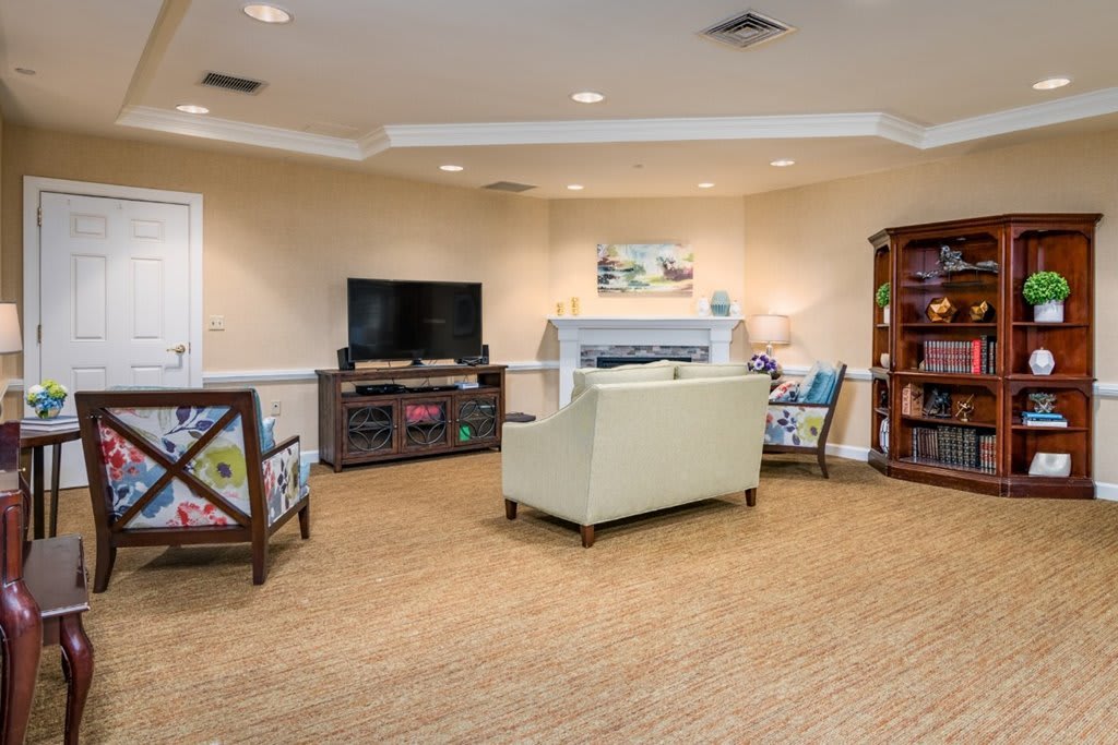 A cozy living room with a television, bookshelf, and comfortable seating.