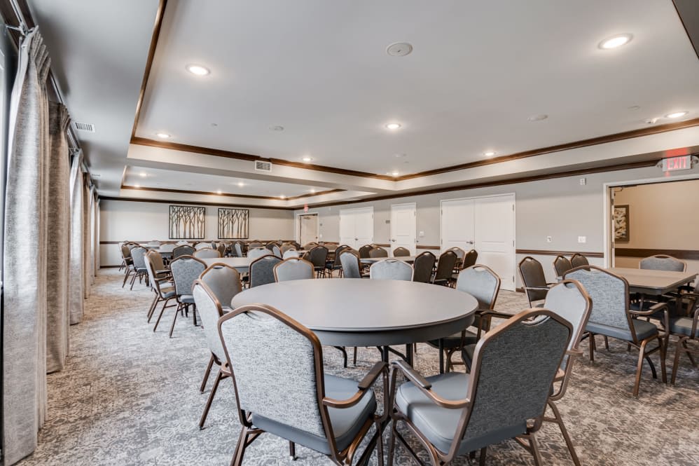 A spacious conference room with round tables and chairs, arranged for an event or meeting.