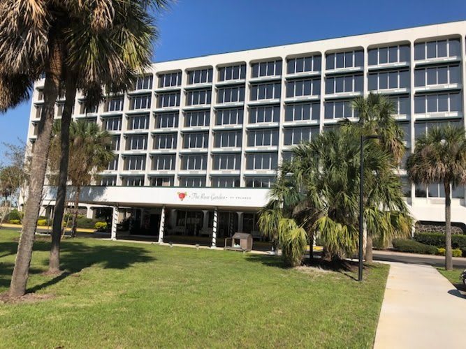 A modern building with palm trees and a well-maintained lawn on a sunny day.