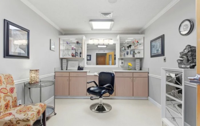 A modern hair salon interior with a styling chair and mirrored shelves.
