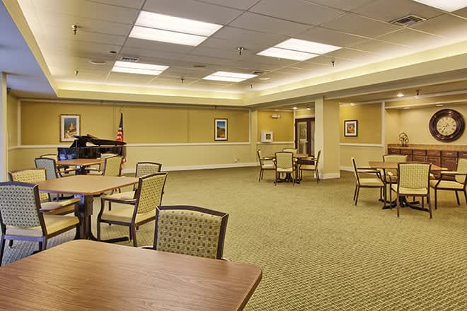 An empty conference room with tables and chairs, well-lit and carpeted.