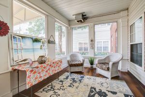 A cozy sunroom with comfortable seating and a decorative rug.