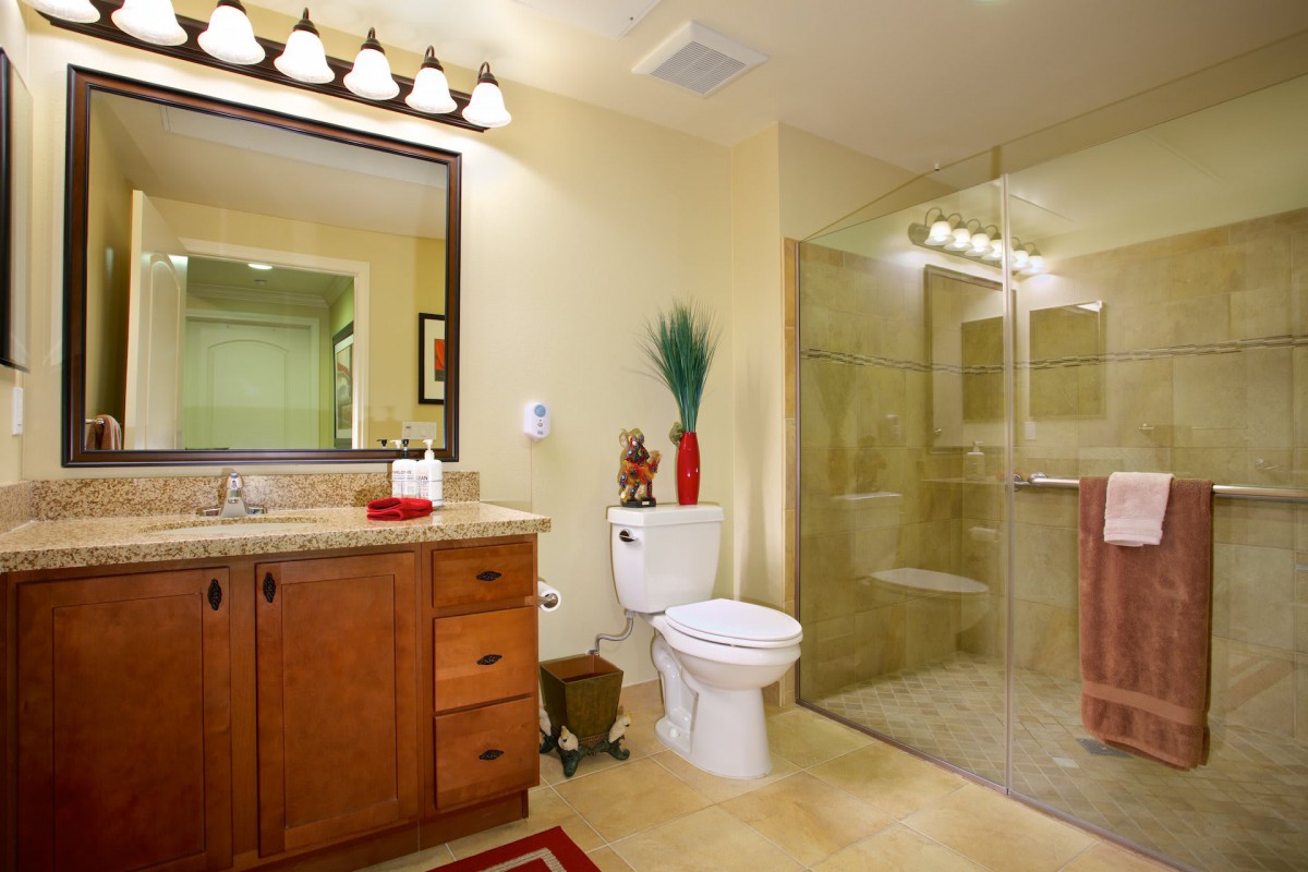 A modern bathroom featuring a glass shower, wooden vanity, and decorative accents.
