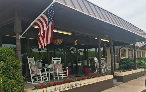 A cozy and inviting porch with rocking chairs, adorned with an American flag.