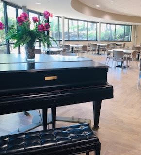 An elegant restaurant interior featuring a grand piano adorned with fresh flowers.