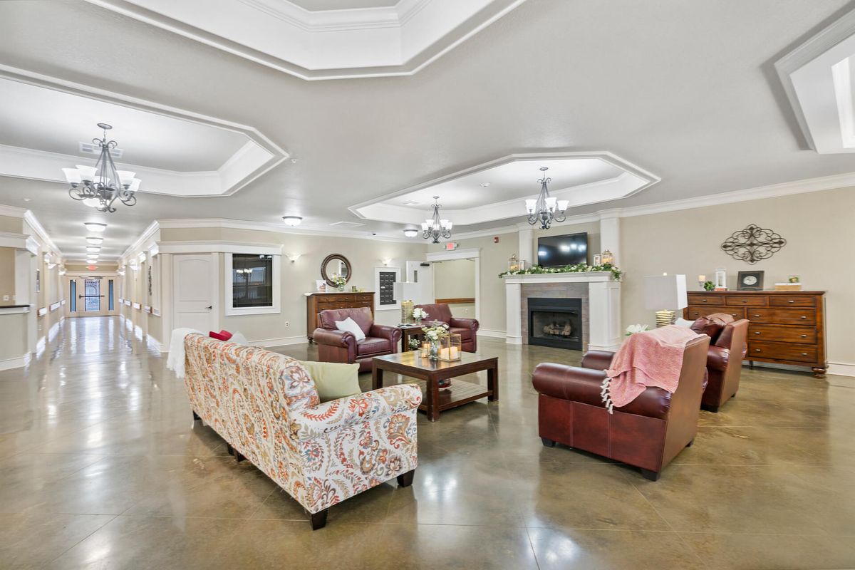 A spacious and elegantly decorated living room featuring comfortable seating, a fireplace, and ceiling lights.