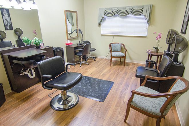A cozy hair salon with styling chairs and mirrors, featuring a warm wooden floor.