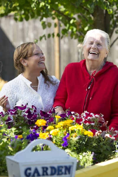 Two women enjoying time together in a colorful garden.
