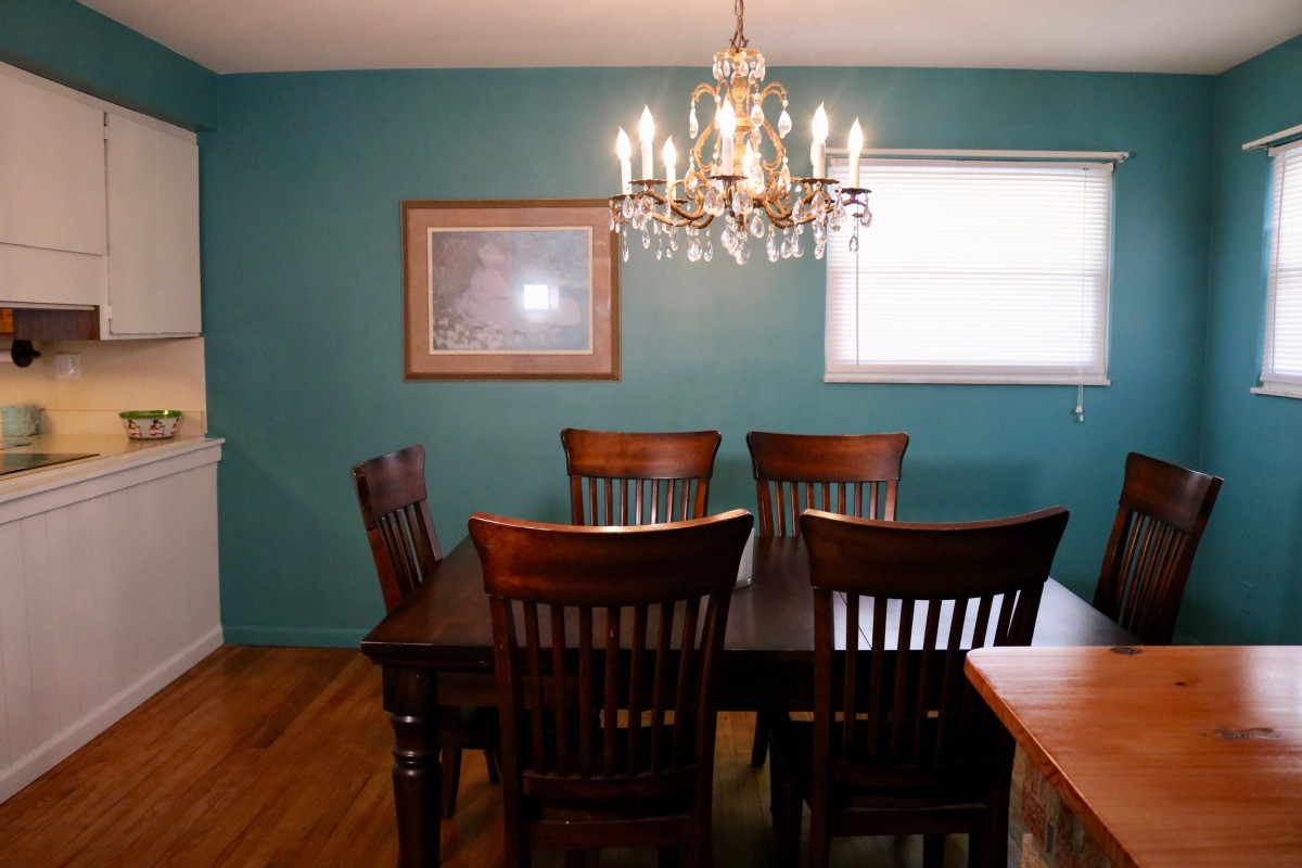 A dining room with a wooden table, chairs, and a chandelier.