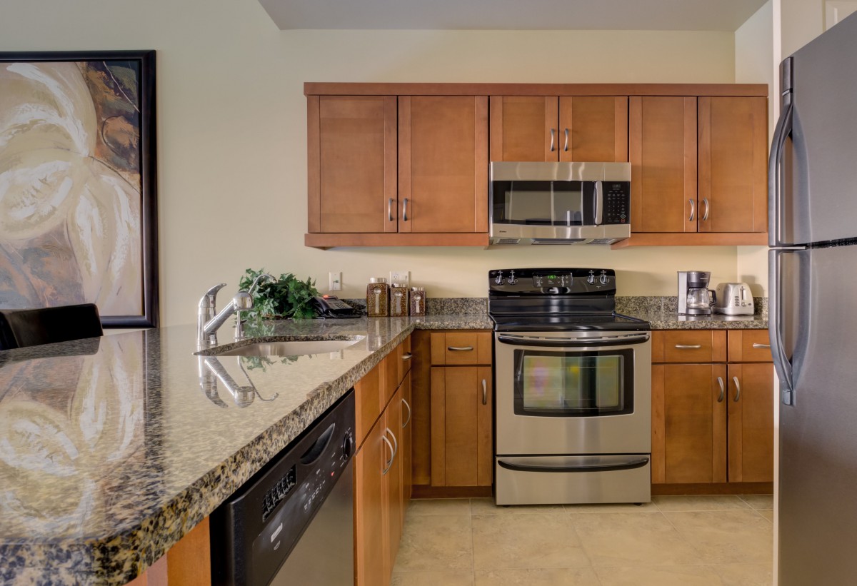 A modern kitchen featuring stainless steel appliances and wooden cabinets.