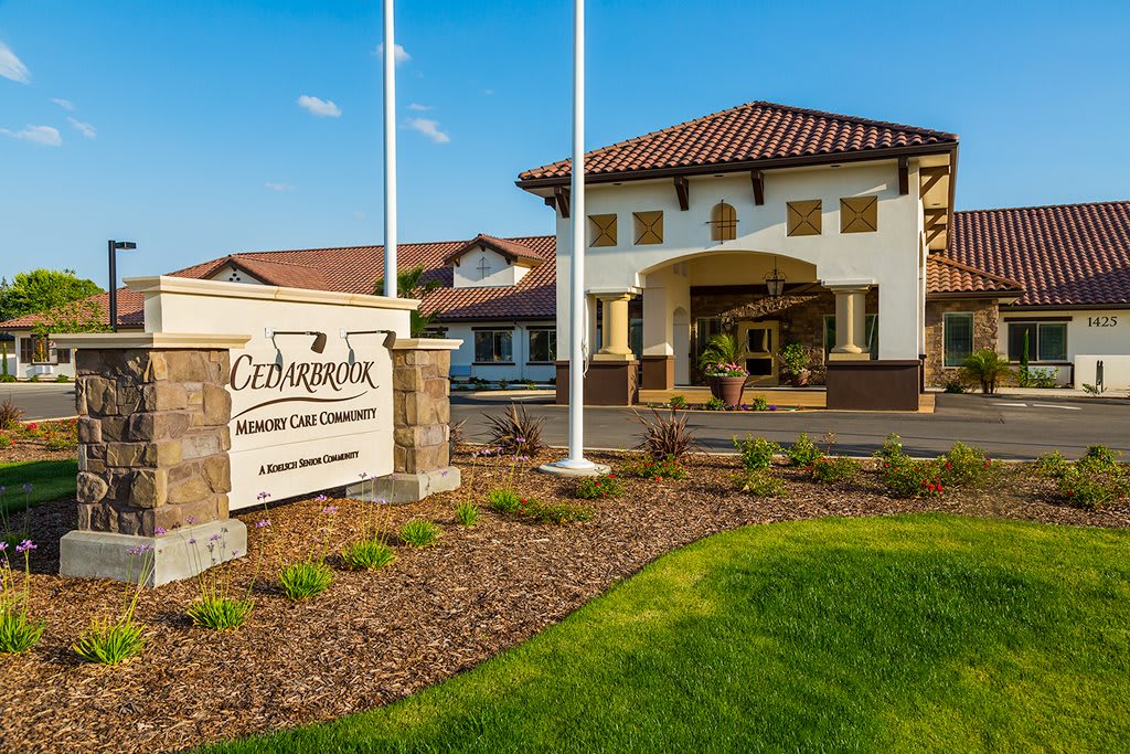Entrance of a building with signage and landscaped grounds on a sunny day.