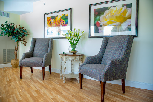 A cozy and stylish interior featuring two gray upholstered chairs, adorned with floral artwork and a small table with decorative plants.