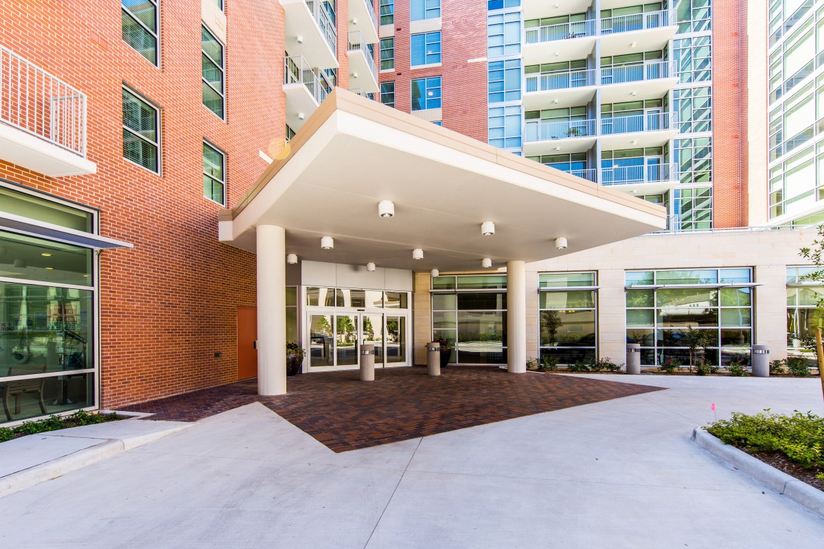 A modern apartment building entrance with a covered portico and glass doors.