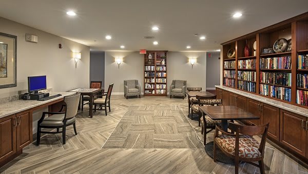 A cozy library interior with tables, chairs, and bookshelves.