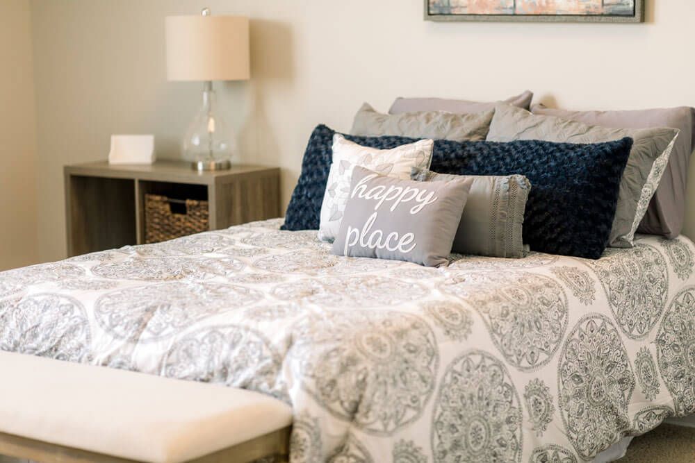 A cozy bedroom with decorative pillows and a stylish lamp on the nightstand.