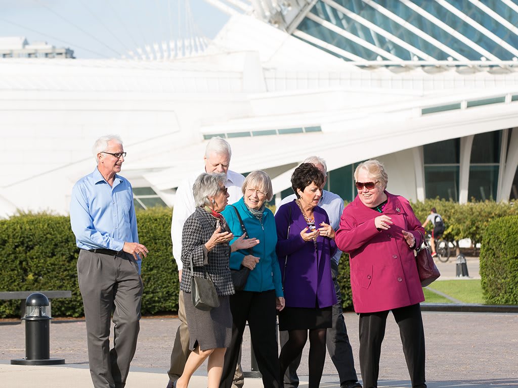 A group of people walking outside near a modern architectural structure.
