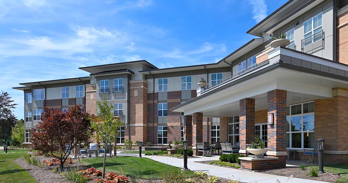 A modern residential building with landscaped surroundings against a clear blue sky.