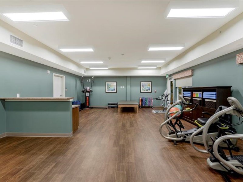 A modern gym interior with exercise equipment and a wooden floor.