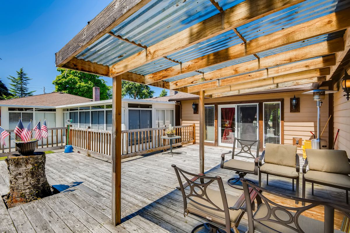 A spacious backyard patio with a wooden pergola and outdoor seating.