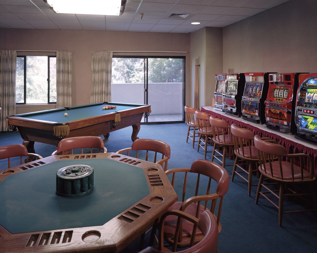 A game room featuring a poker table, slot machines, and a billiards table.